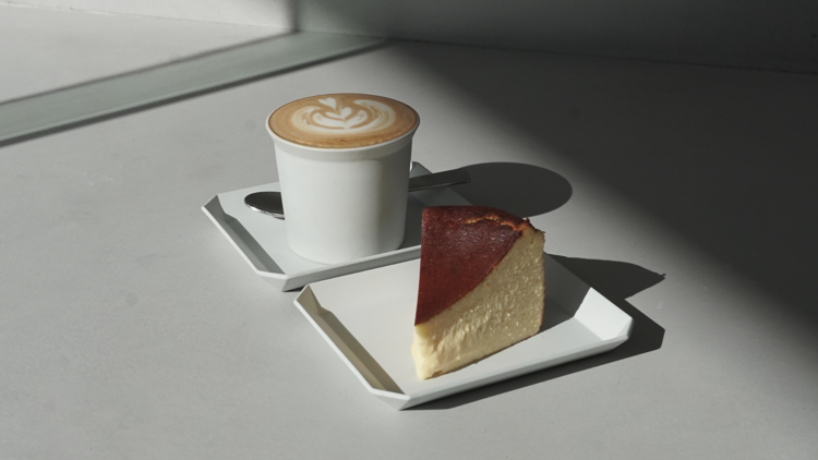 A plate of cheesecake next to a plate of coffee