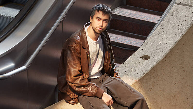 picture of Alex G sitting on an escalator