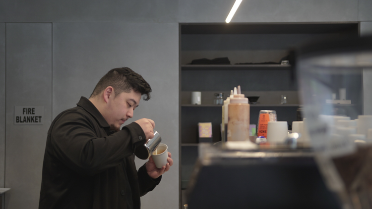 A barista pouring a coffee