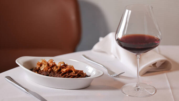 A dish of dry-aged Victorian duck breast parmentier with a glass of red wine.