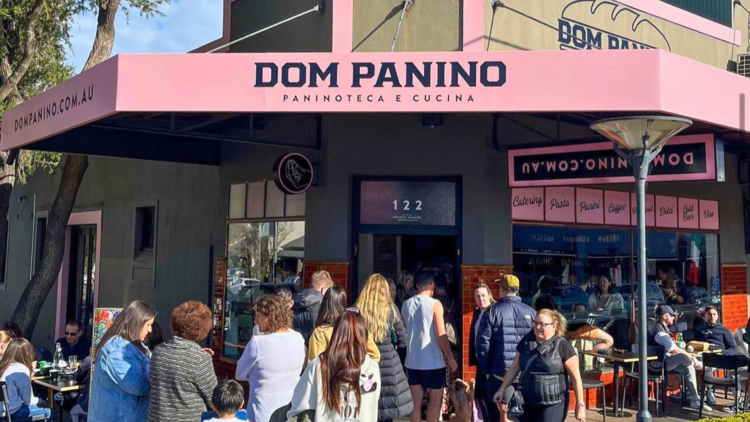 A pink sandwich shop with a queue out the door