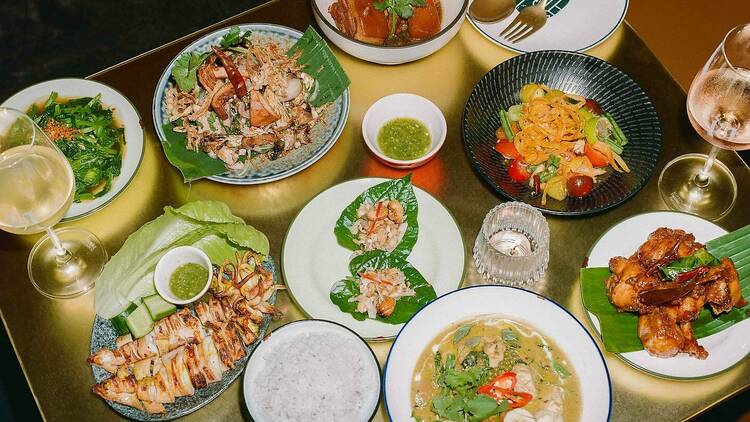 Assorted Thai dishes laid out on a gold table.