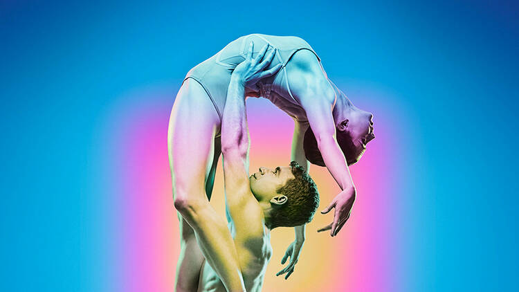 A male dancer lifting a female dancer in a back bend above his head 