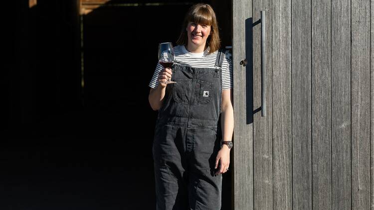 Emily Kinsman from ECK Wines standing by her cellar door with a glass of red wine.