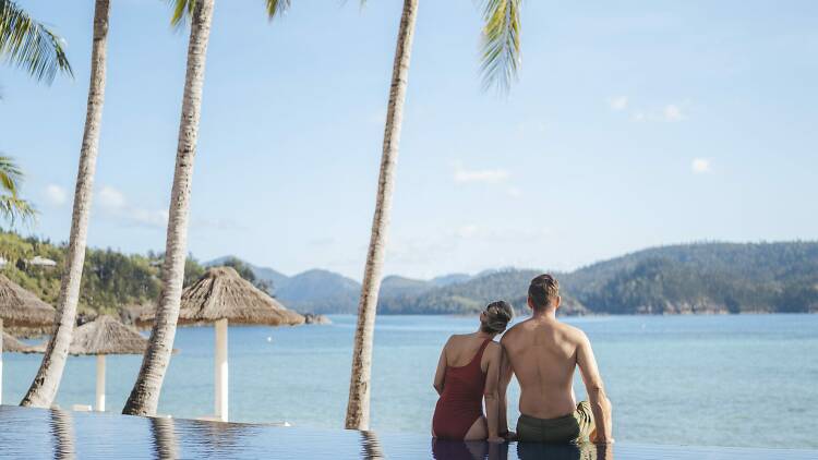 Couple relaxing on the edge of the infinity pool at Beach Club in Hamilton Island