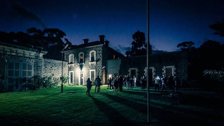 People gather on a lawn outside J Ward on a dark night