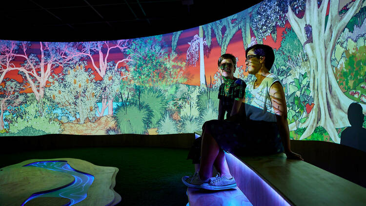 Two people sit in a video projection installation.