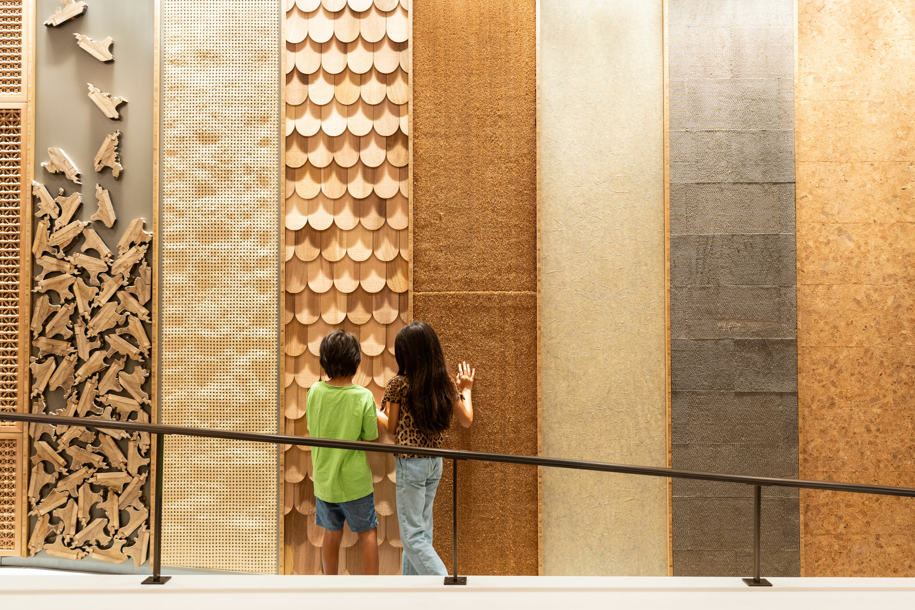 Two kids feel a wall of different woods.