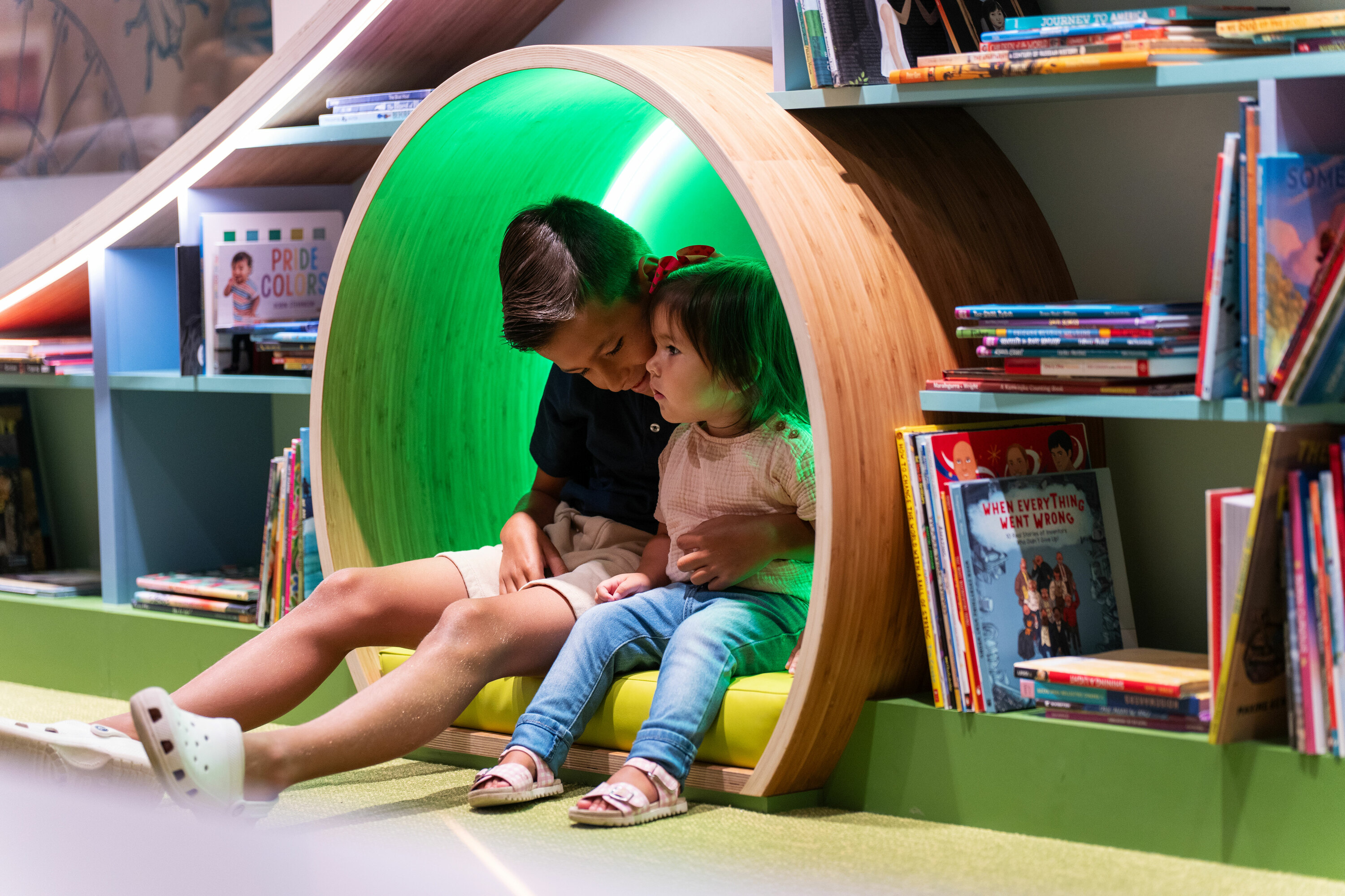 Two kids sit in a reading nook.