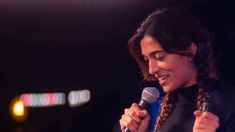 A comedian holds a microphone on stage.