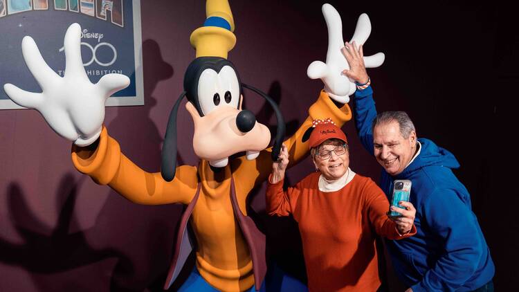 Two people taking a photo with Goofy