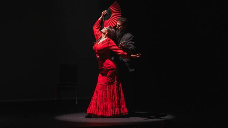 picture of a flamenco dancer in a red dress with a fan and a man behind her