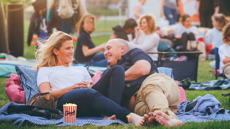 Couple on a picnic blanket enjoys an evening at the sunset cinema