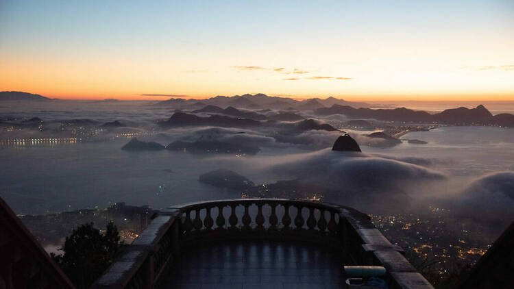 Vista do alto do Cristo Redentor ao por do sol com o céu rosado