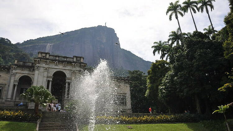 Um chafariz na frente de uma construção antiga onde fica o Parque Lage