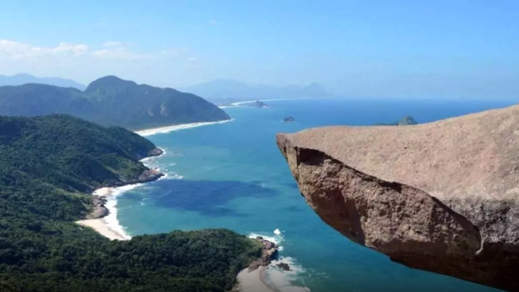 Ponta de uma pedra que parece à beira do penhasco, com o mar ao fundo