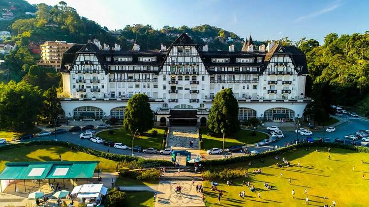 No final de um jardim gramado, um palácio gigantesco de paredes brancas com telhado marrom