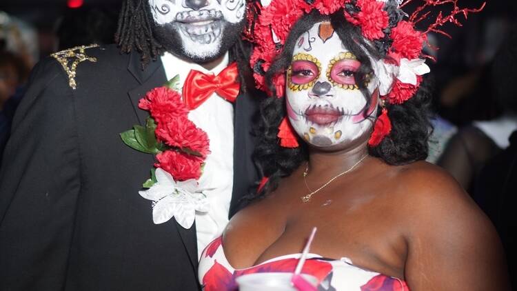Two people dressed up in sugar skull-looking costumes.