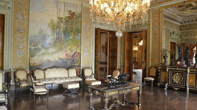 Interior do Museu da República, com mobiliário antigo, um sofá e uma mesa de centro, além de um gigantesco candelabro aceso