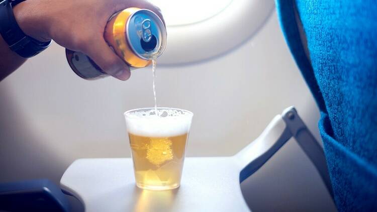 Beer can being poured in the sky on an airplane