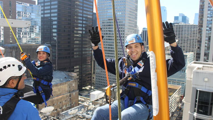 Two people preparing to rappel down a building
