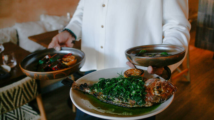 A waiter holding dishes at Zama