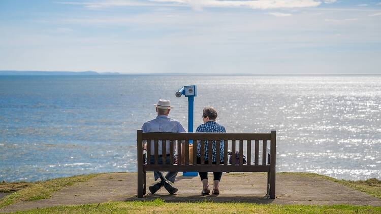 Elderly couple on a bench in the UK, looking out to see