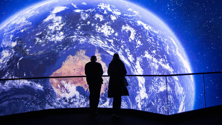 A giant image of the globe with two people silhouetted in front of it. 