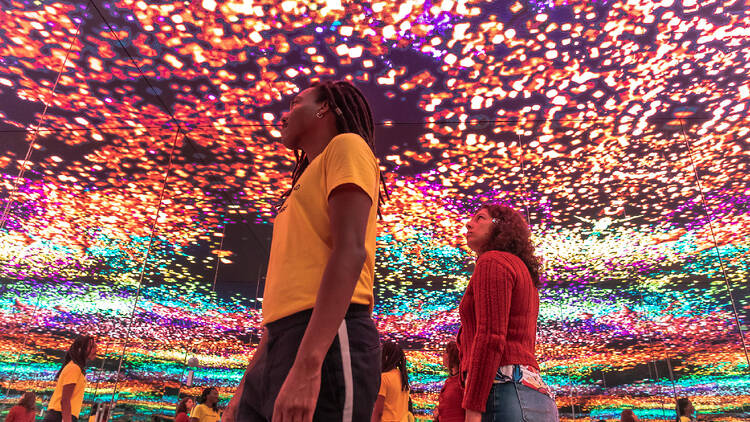 Duas mulheres encaram um teto de luzes coloridas