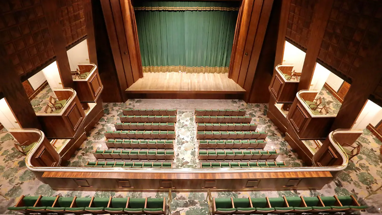 Plateia do Teatro Copacabana Palace vista de cima, com suas poltronas de veludo verde, e o palco fechado por uma cortina no mesmo tom