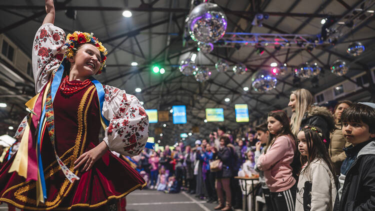 A woman wearing traditional European dress performs a dance. 