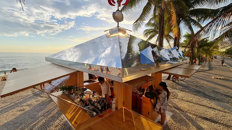 Um quiosque à beira-mar com arquitetura geométrica e telhado espelhado