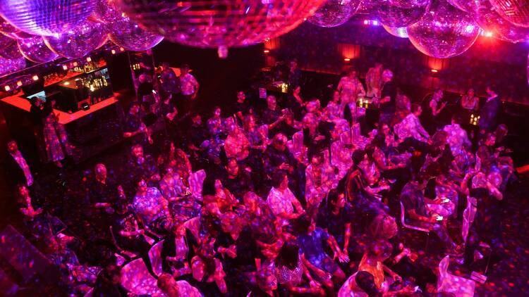 A group of people inside the theater for AWESTRUCK, bathed in pink light.