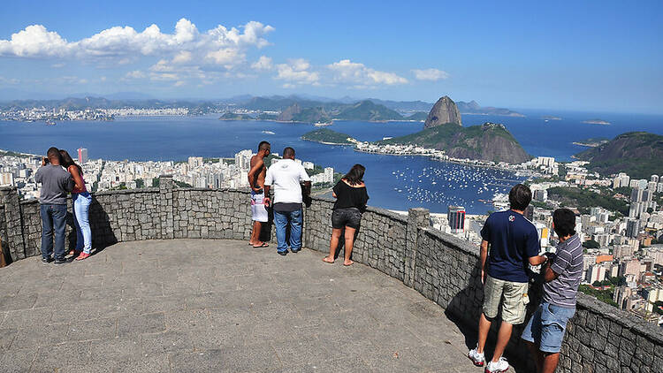 Pessoas observam a vista de um mirante que se abre para o Pão de Açúcar