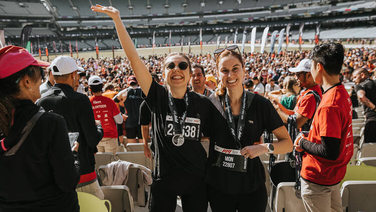 Two women with running bibs are smiling. 