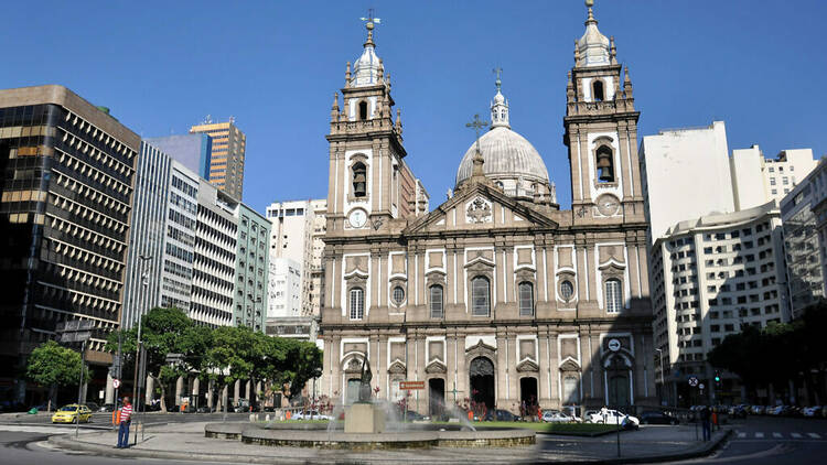 Aos fundos, uma gigantesca edificação com duas torres e uma cúpula central