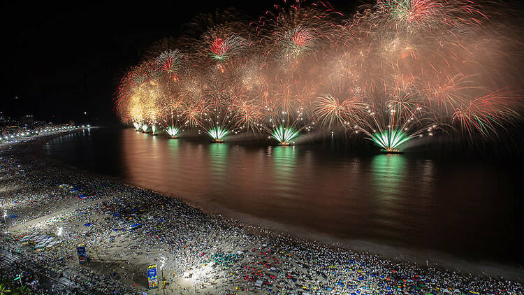 Fogos de artifício explodem no mar à noite durante a festa de Réveillon na Praia de Copacabana