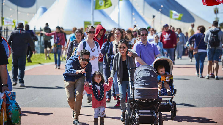A family walking through the Melbourne showgrounds smiling. 