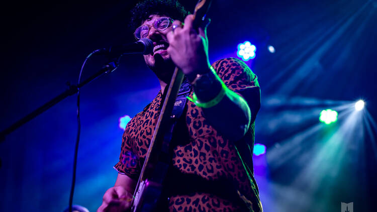 A performer plays a guitar onstage. 