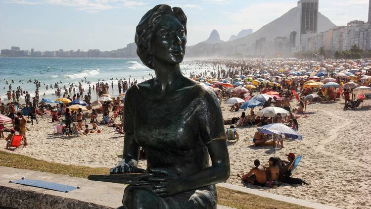 Estátua de bronze da escritora Clarice Lispector com a Praia do Leme ao fundo
