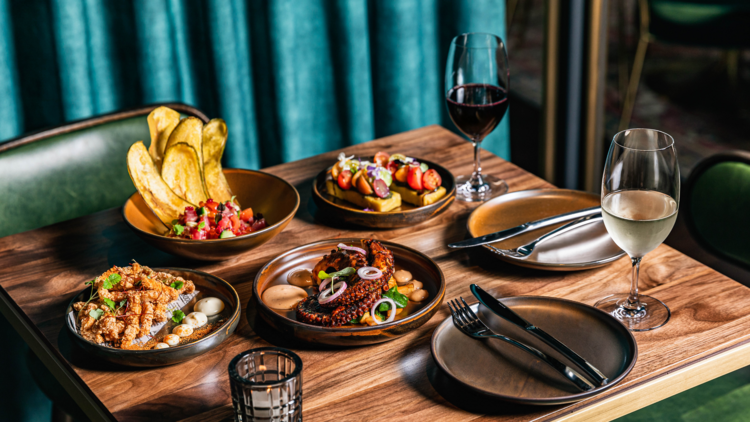 A table of share plates with two glasses of wine