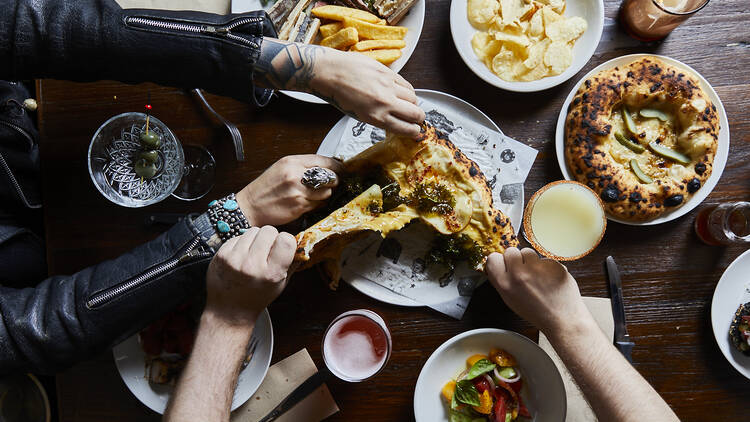 Flatlay of people ripping a pizza