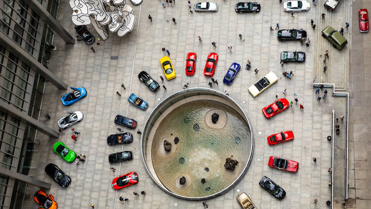 Cars parked around a fountain. 