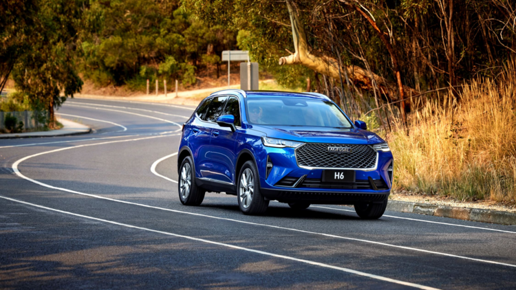 A blue Haval HG drives on a road with trees