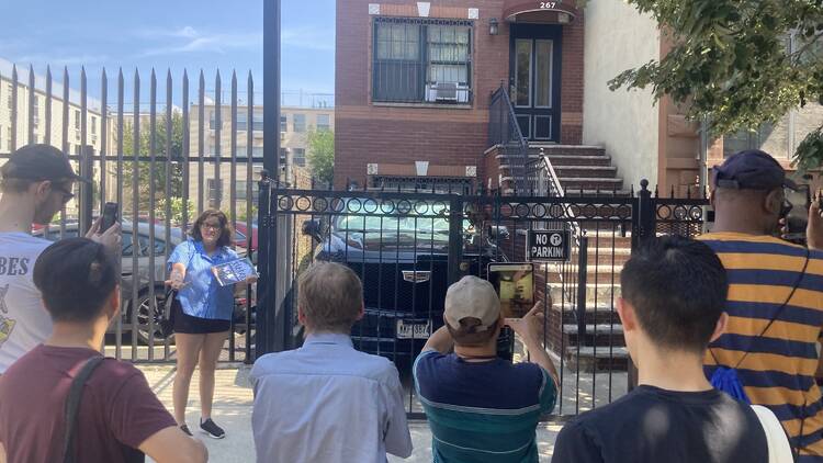 A woman leads a tour group in front of a red brick building.