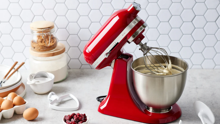 A red KitchenAid mixer alongside eggs and raspberries