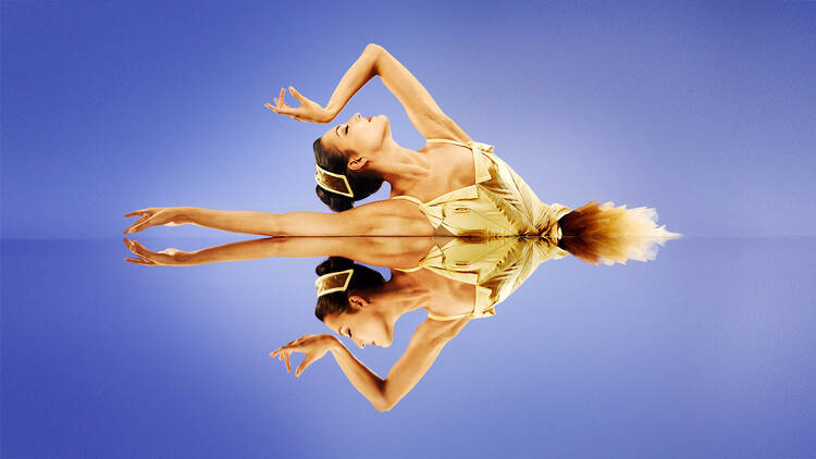 A ballet dancer poses next to a mirror.