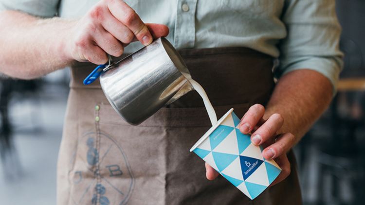 A barista pours milk into a Jamaica Blue coffee cup