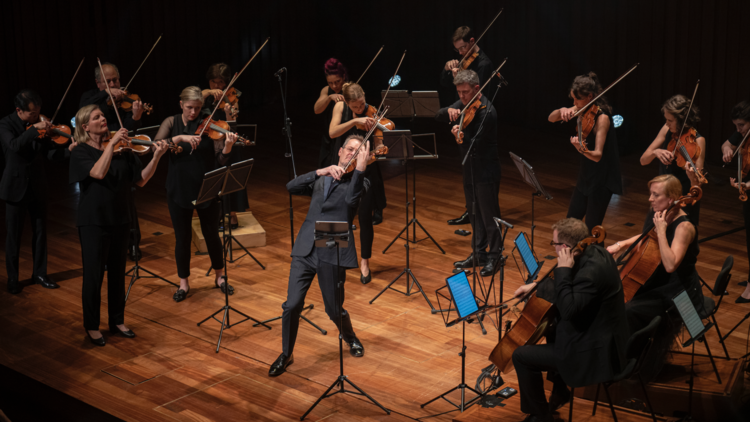 A violinist playing onstage with an orchestra
