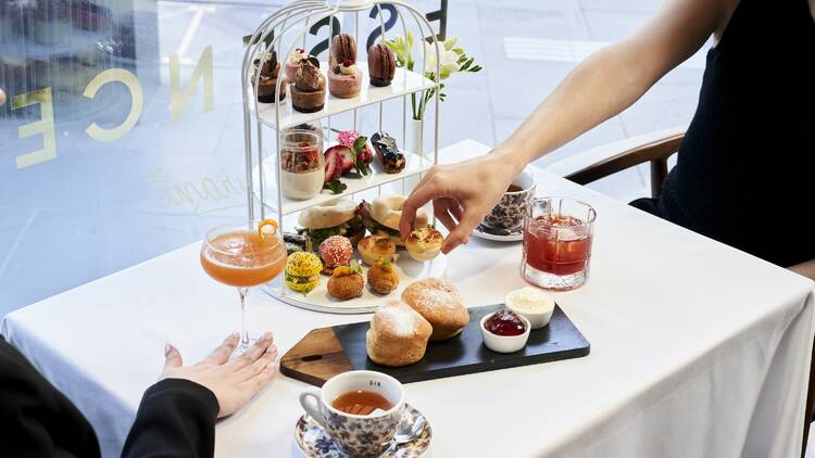 A pair of guests enjoying high tea from a three-tiered tray at Marriott Hotel.